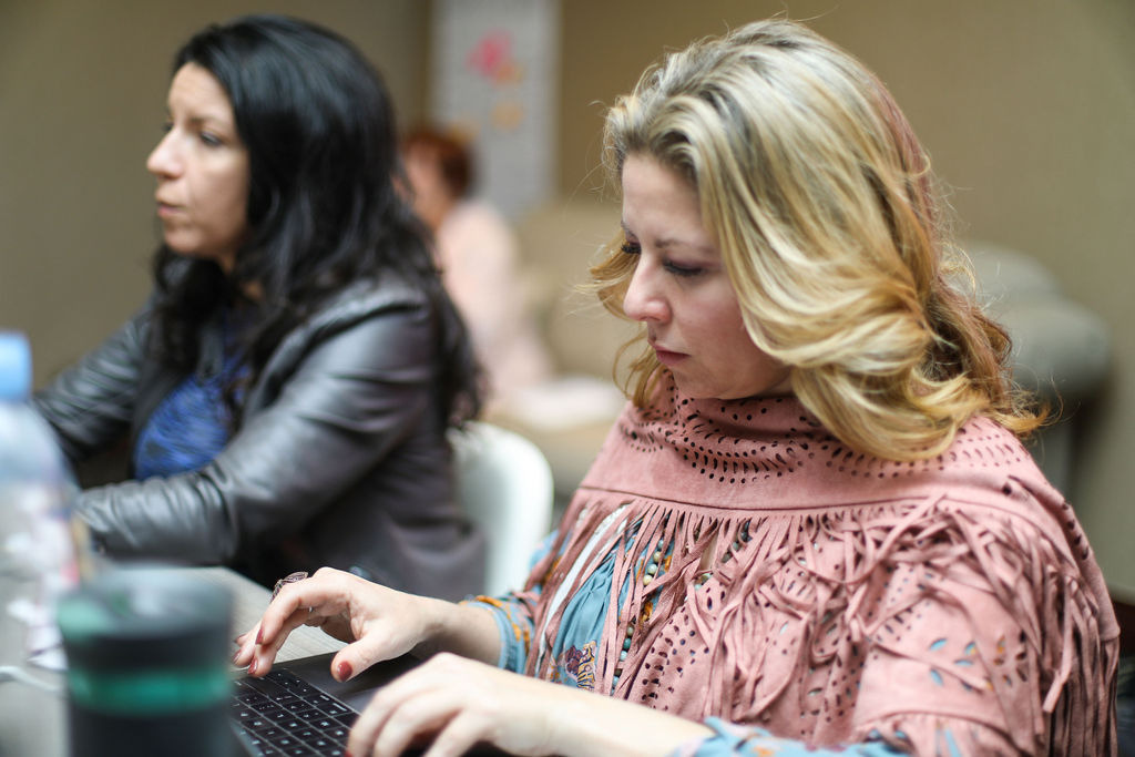 Two attendees working side by side on their laptops