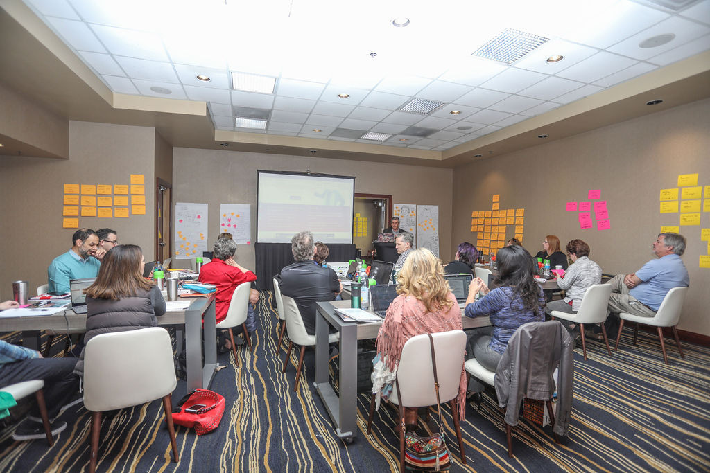 A workshop room with participants working at long tables