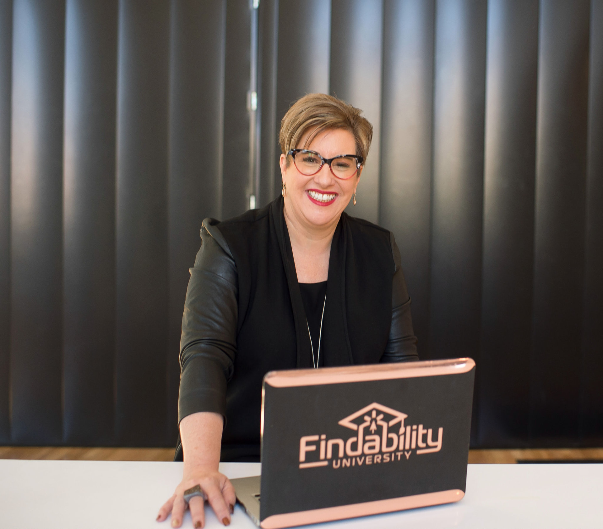 Heather Lutze smiling behind her Findability University laptop