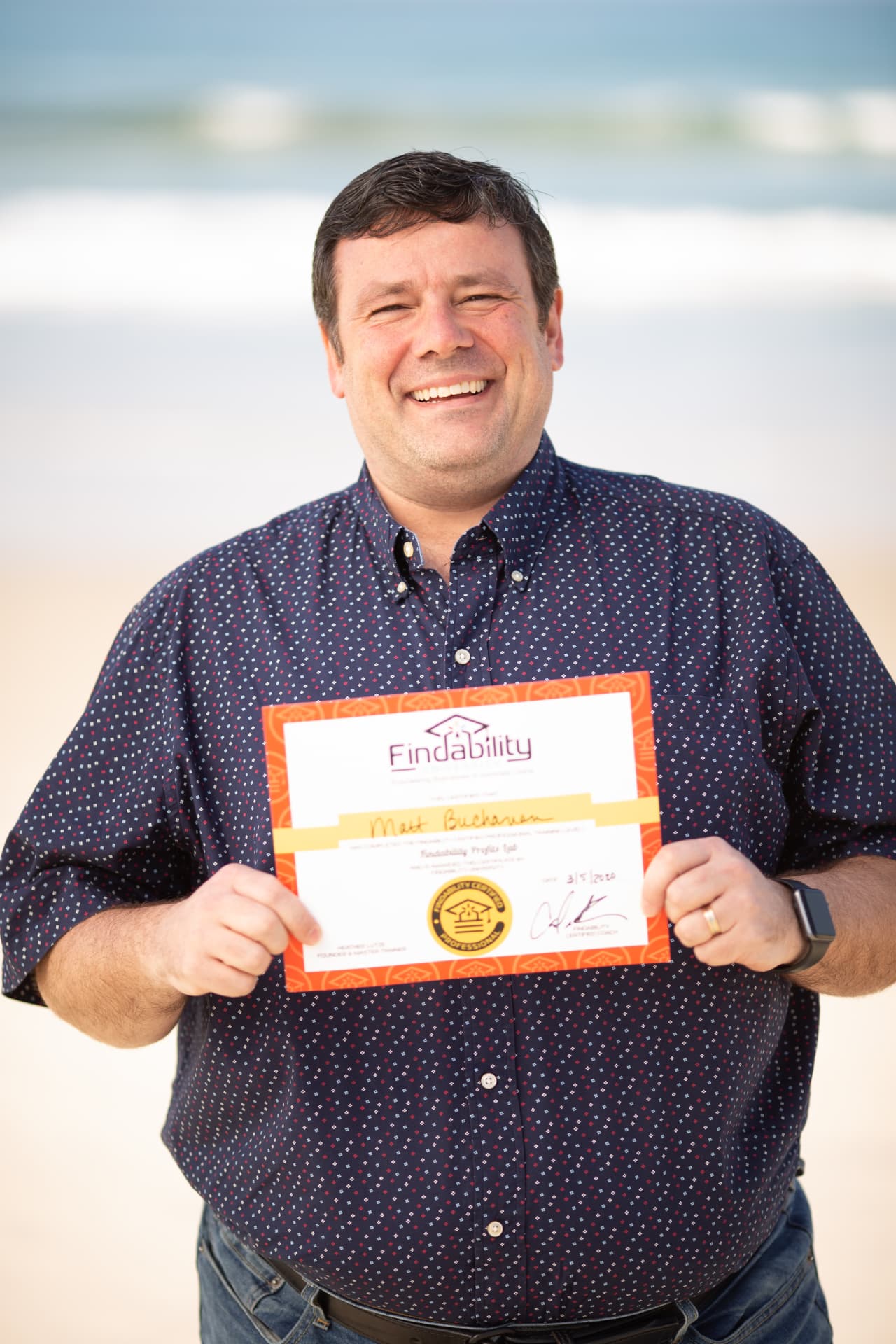 Workshop graduate holding his Findability certificate on the beach